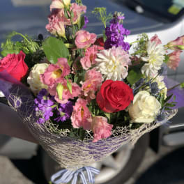 Mixed bouquet of pink, red, white, and purple flowers wrapped in mesh