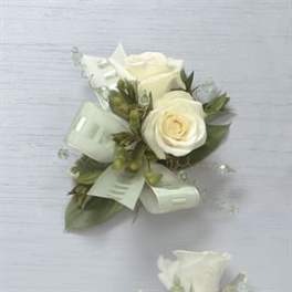 White rose boutonniere with ribbon and greenery