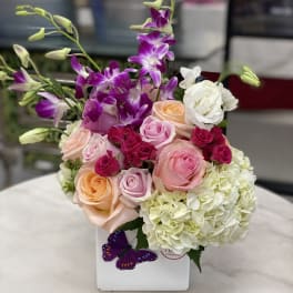 Mixed bouquet of roses, orchids, and hydrangeas in a white box