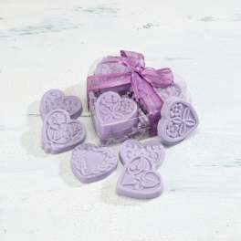 Heart-shaped lavender soaps in a clear heart box with a purple ribbon and soaps scattered around it.