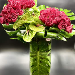 Pink rose bouquet with green anthuriums in a tall glass vase