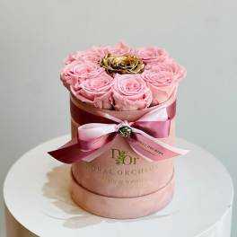 Pink roses arranged in a round hat box with a ribbon bow