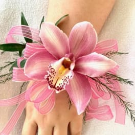 Pink orchid wrist corsage with ribbon on a person's wrist