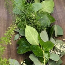 Loose garland of assorted green foliage on a wooden surface