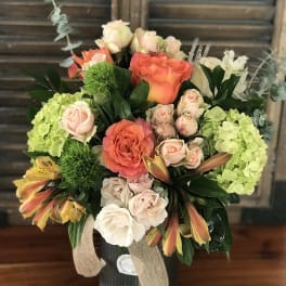 Mixed bouquet in a ribbed vase with coral and blush roses
