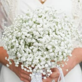 Bride holding a white baby's breath bouquet with ribbon
