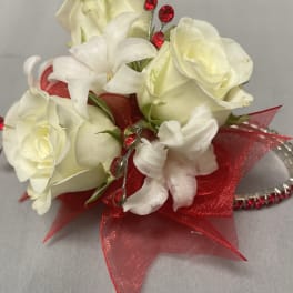 White rose wrist corsage with red ribbon and red rhinestones on a silver bracelet
