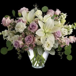 Bouquet of white lilies and lavender roses in a clear glass vase