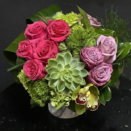 Bouquet of pink and lavender roses with a succulent in a low vase