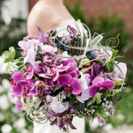 Bride holding a bouquet of purple orchids and white ribbon curls