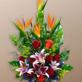Tropical bouquet with red roses and pink lilies in a white container