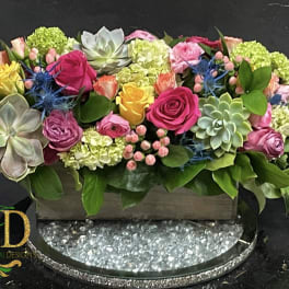 Rectangular floral arrangement with roses, succulents, and hydrangeas in a low container