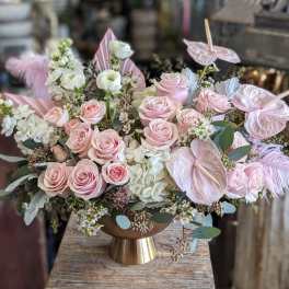 Pink roses and white blooms in a gold vase with pink anthuriums