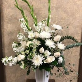 White floral arrangement in a tall white vase with long green stems