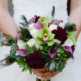 Bridal bouquet with purple calla lilies, white orchids, and peacock feathers