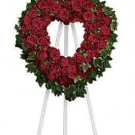 Heart-shaped standing wreath of red roses on a white easel