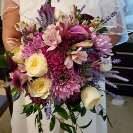 Bride holding a pink and cream bouquet with purple accents