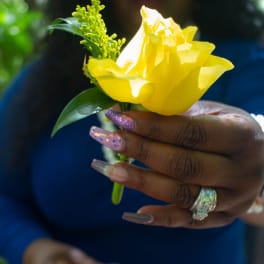 Yellow rose boutonniere held in a hand