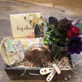 Gift basket with a small flower arrangement, candle, and stationery items
