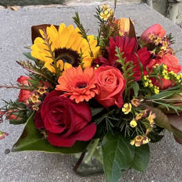 Bouquet of sunflowers, roses, and gerbera daisies in a glass vase