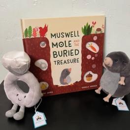 Two plush moles beside a children's book on a table