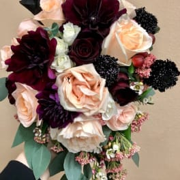 Bouquet of blush and burgundy roses with dark blooms and greenery