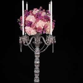 Pink and purple floral arrangement on a tall crystal candelabra.