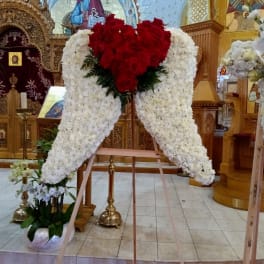 Large white floral standing spray with red roses in a church