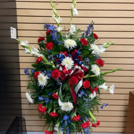 Standing floral spray with red, white, and blue flowers on a metal easel