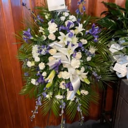 Standing floral spray with white and purple flowers and a white ribbon