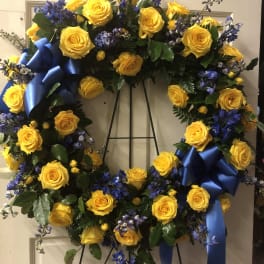 Yellow rose wreath with blue ribbon accents on a stand