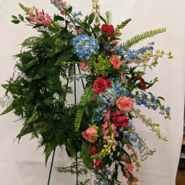 Large standing floral spray with roses, hydrangeas, and blue blossoms