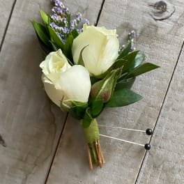 White rose boutonniere with purple filler flowers and green leaves