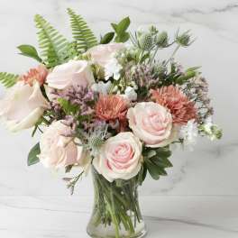 Pink and white roses with coral mums in a glass vase