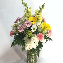 Mixed bouquet of yellow, pink, and white flowers in a glass vase