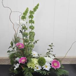 Low floral arrangement with pink gerberas, white daisies, and green blooms