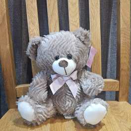 Gray teddy bear with a pink ribbon sitting on a wooden chair