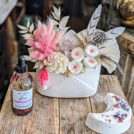 Small floral gift arrangement in a white container with pink and white dried flowers