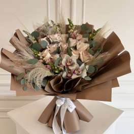 Bouquet of pale roses and orchids wrapped in brown paper