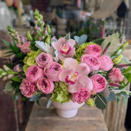 Pink roses and orchids arranged in a white vase