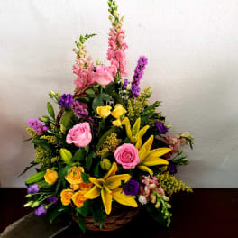 Mixed bouquet of pink, yellow, and purple flowers in a basket