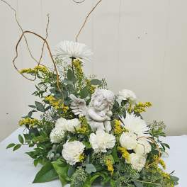 White flowers arranged around a small angel figurine with curly branches