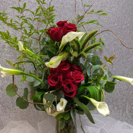 Red roses and white calla lilies in a glass vase