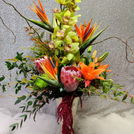 Tall tropical arrangement with orchids, bird of paradise, and lilies in a vase
