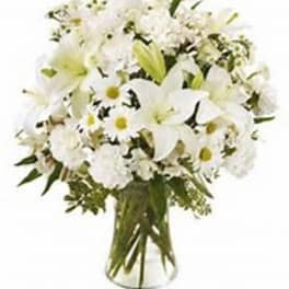 Bouquet of white lilies, daisies, and carnations in a clear glass vase