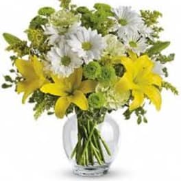 Round glass vase with yellow lilies, white daisies, and green button flowers