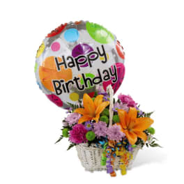 Birthday balloon with orange lilies and mixed flowers arranged in a white basket.