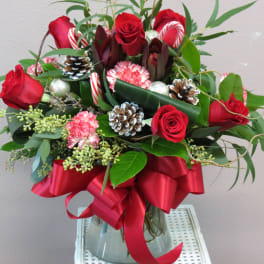 Red roses and candy canes arranged in a glass vase with a red ribbon