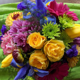 Bright mixed bouquet with roses, daisies, and tulips on green fabric