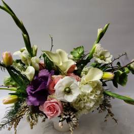 Mixed bouquet with white calla lilies, pink roses, and purple blooms in a vase